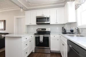 La cuisine est équipée de placards blancs et d'un four avec plaques de cuisson. dans l'établissement New One Bedroom Apartment Near Lake Winnipesaukee, à Wolfeboro