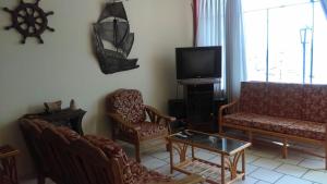 een woonkamer met een bank en stoelen en een tv bij Casa de playa tortugas in Casma