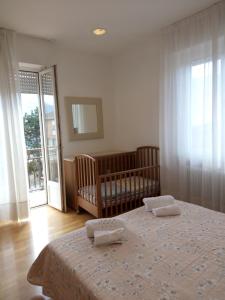 a bedroom with a crib and a bed with two towels at Casa Alby in Levico Terme