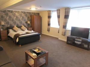 a living room with a bed and a flat screen tv at The Southgate B&B in Filey
