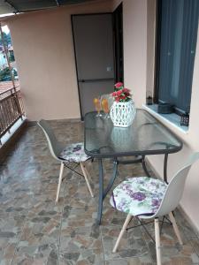 szklany stół z 2 krzesłami i wazon z kwiatami w obiekcie Dimitra's Garden Villa w mieście Kallirákhi