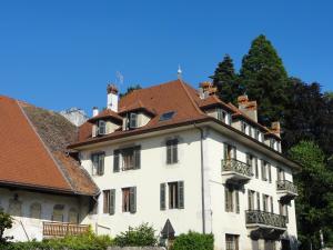 un grand bâtiment blanc avec un toit rouge dans l'établissement Studio La Savoyarde - Vision Luxe, à Menthon-Saint-Bernard