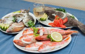 three plates of seafood on a table with a glass of wine at Tylos Beach Hotel in Kato Pyrgos