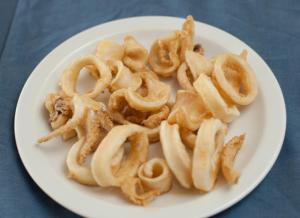 a plate of food with onion rings on a table at Tylos Beach Hotel in Kato Pyrgos