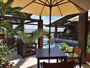 a table with an umbrella next to a pool at Alfa Beach in Cacha Pregos