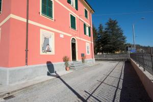 una persona está mirando por la ventana de un edificio rosa en Il grappolo -affittacamere- en Gavi