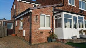 a extension to a brick house with a white door at cosy annex close to leeds airport in Guiseley