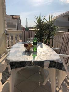 una mesa blanca con un bol de fruta y una botella en Villa Domora apartments, en Trogir