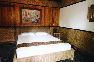 a bedroom with a bed and a painting on the wall at Mini Tiga Homestay in Pangandaran