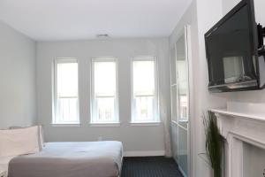 a room with a bed and a tv and windows at Stylish Studio on Newbury St, THIS IS BOSTON! #12 in Boston