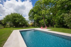 a swimming pool with two chairs next to a yard at Chambres d'hôtes Le Clos des Tilleuls in Demigny