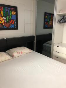 a bedroom with a white bed and a mirror at Baln Camboriu - Beira mar in Balneário Camboriú