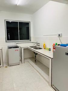a white kitchen with a sink and a refrigerator at Town City Home sweet home in Kuala Terengganu