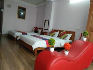 a hotel room with two beds and a red chair at Chau A Hotel in Hải Dương