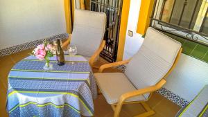 uma mesa com duas cadeiras e um vaso de flores sobre ela em La Casita Blanca - Vistabella Golf em Orihuela