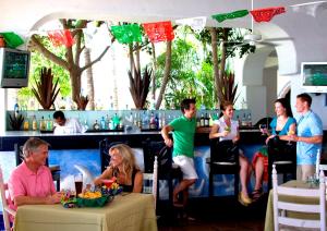 a group of people sitting at a bar at Pueblo Bonito Los Cabos Blanco Beach Resort - All Inclusive in Cabo San Lucas
