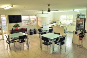 a kitchen with tables and chairs and a kitchen with a tv at Isla House Greenslopes in Brisbane