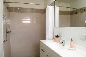 a bathroom with a sink and a shower with a mirror at Isla House Greenslopes in Brisbane