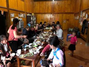 Un gruppo di persone seduti intorno a un tavolo che mangiano cibo di ChienDe Homestay a Sa Pa