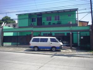 une camionnette blanche garée devant un bâtiment vert dans l'établissement Guesthouse Dos Molinos B&B, à San Pedro Sula