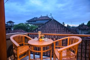 a wooden table and chairs on a balcony at Kamar Suci House in Ubud