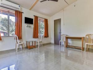 a living room with a table and chairs and a tv at Bahar Deluxe in Dapoli