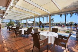 a restaurant with tables and chairs and a pool at Comfort Resort Waters Edge in Port Macquarie