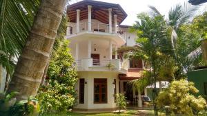 een wit huis met palmbomen ervoor bij Helianto Social Villa in Bentota