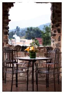 una mesa con dos sillas y un jarrón con flores. en Meson de Maria en Antigua Guatemala