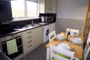 a kitchen with a table and a sink and a dishwasher at Sealladh A’ Chaolais (Eriskay) in Eriskay