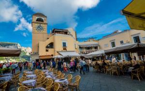 a group of tables and chairs with a clock tower at La Perla Blu in Capri