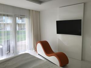 Wellness Apartments in Velence في فيلينس: غرفة نوم بسرير وكرسي بجانب نافذة