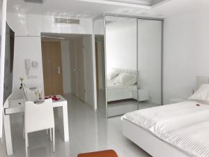 Wellness Apartments in Velence في فيلينس: غرفة نوم بيضاء مع سرير ومرآة