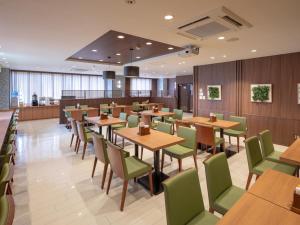 a restaurant with wooden tables and green chairs at Central Hotel Takeoonsen Ekimae in Takeo