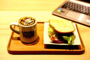 a sandwich and a cup of coffee next to a laptop at 26 Inn in Yilan City