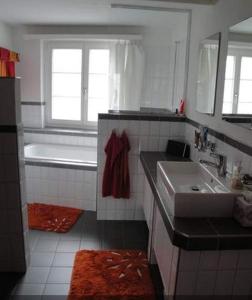 Baño blanco con bañera y lavamanos en Rheintal-Zimmer, en Altstätten