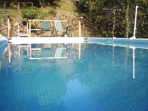 a blue swimming pool with a chair and a table at Casale Camalda in Serravalle