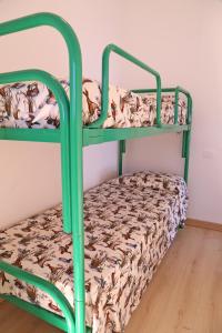 Cette chambre comprend 2 lits superposés avec des cadres verts. dans l'établissement Residence Tamerici, à Caorle
