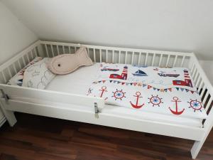 a white crib with a bed with a nautical bedding at Wohnung Nordseebriese in Norden