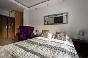 a bedroom with a large bed and a purple chair at Apartament SZEROKA in Gdańsk