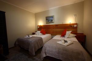 a hotel room with two beds with red pillows at Kaapsche Hoop Gastehuis in Kaapsehoop