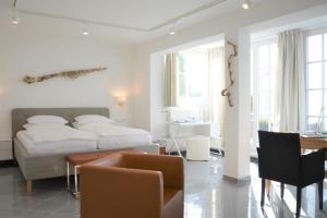 ビンツにあるAtelier-Appartement Ambienta im Zentrum von Binzの白いベッドルーム(ベッド1台、テーブル、椅子付)