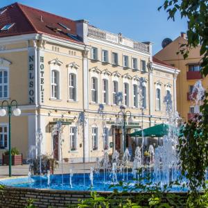 a building with a fountain in front of it at Nelson Hotel in Hajdúszoboszló