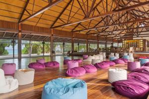 Hanimaadhoo的住宿－赤腳生態酒店，铺有木地板的客房,配有紫色和白色豆袋