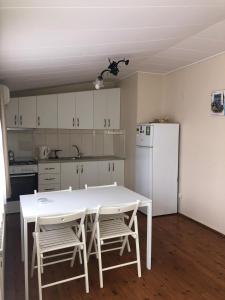 een keuken met een witte tafel en stoelen en een koelkast bij Büyükada Apart Hotel - Yeni Apart in Buyukada