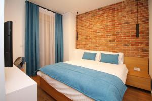 a bedroom with a large bed with a brick wall at Elena Apartment&Spa in Zlatibor