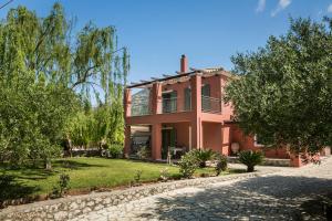 a pink house with a cobblestone driveway at VILLA MARITINA in Kefallonia