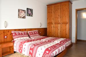 a bedroom with a bed and a wooden cabinet at Appartamenti Osti Sansoni Mariarosa in Andalo