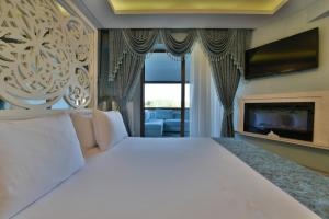 a bedroom with a large white bed and a fireplace at Kartepe Köşkü in Kartepe