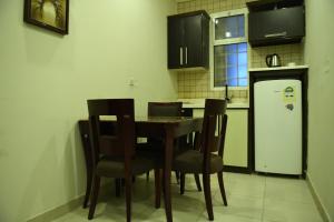 cocina con mesa, sillas y nevera en Hudo Al Masa Apartment Hotel en Riad